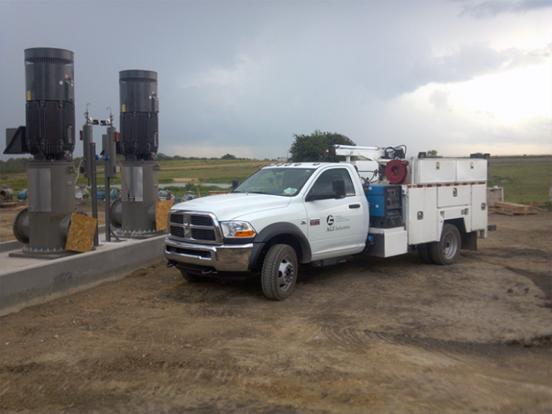 AGI truck in a field next to pumps